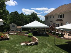two outdoor tent rentals at backyard party with table and chairs